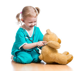 Adorable child with clothes of doctor playing with plush toy