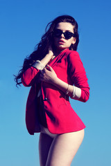 fashion portrait. sexy girl in red coat posing against blue sky