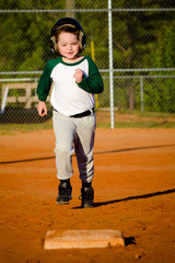 Young child running bases while playing baseball