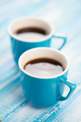 Two turquoise espresso cups on wooden boards, close-up