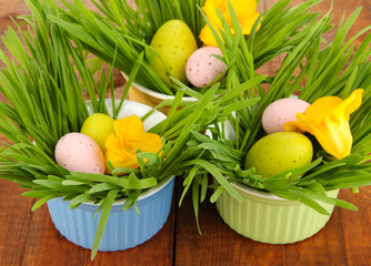 Easter eggs in bowl with grass on wooden table close up