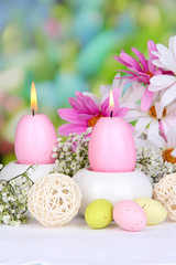 Easter candles with flowers on bright background