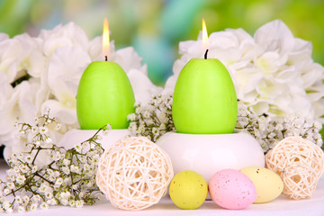 Easter candles with flowers on bright background
