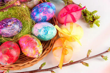 Beautiful Easter eggs in wicker basket on light background