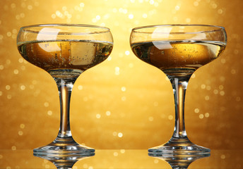 Two glasses of champagne on bright background with lights