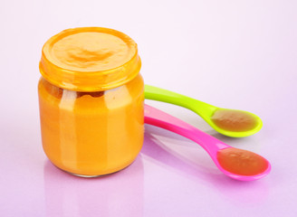 Baby food with weaning spoons on purple background