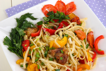 Noodles with vegetables on plate on wooden table