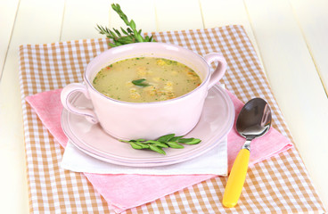 Nourishing soup in pink pan on wooden table close-up