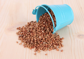 Overturned bucket with grains on wooden background