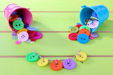 Fototapeta premium Colorful buttons strewn from bucket on wooden background