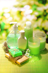 Cosmetics bottles and natural handmade soap on green background