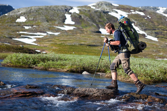 Wanderer beim &uuml;berqueren von Stromschnellen in Norwegen