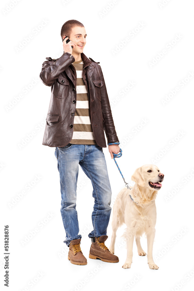 Canvas Prints Full length portrait of a young man walking a dog and talking on