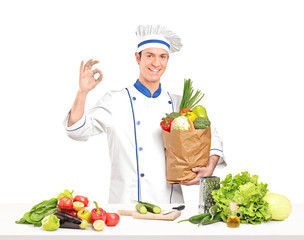 Male chef holding a bag full of healthy vegetable ingridients ne