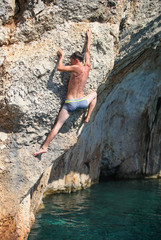 Deep water soloing, male rock climber on cliff