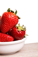Strawberries in white plate on the wooden board. Isolated