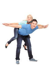 Full length portrait of  a happy young couple posing piggyback