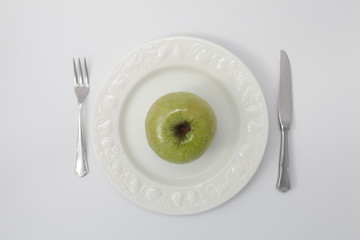Green apple on white dish from above