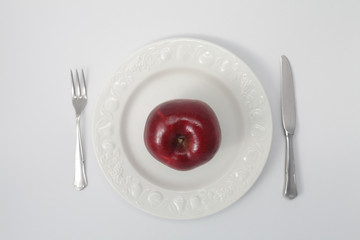 Red apple on white dish from above