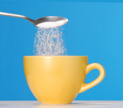 Sirviendo cucharada de az&uacute;car en una taza de caf&eacute;,t&eacute;.