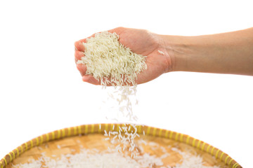 Hand releasing rice grain into a wicker tray