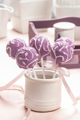Lilac cake pops decorated lavishly decorated with icing.
