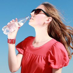 portrait of a young woman drinking mineral water on the beach 