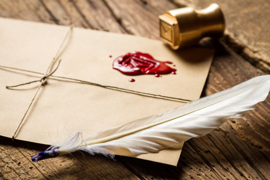 Closeup of feather on envelope with red sealant and metal stamp