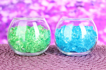 Glasses with colorful decorative stones on bright background