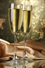 Two glasses of champagne on bright background with lights