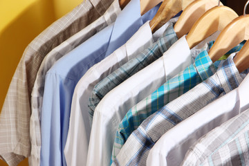 Men's shirts on hangers on yellow background