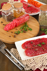 Tasty salami on plate and board on wooden table close-up