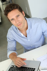 Man with blue shirt working on laptop