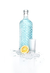 Bottle of vodka with small beaker glass and lemon