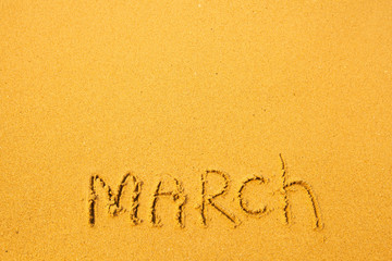 March - written in sand on beach texture
