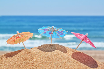 Small beach umbrellas on a beach on a background of the sea.