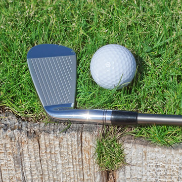 Golf stick and ball support wooden close-up on the grass.