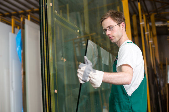 Glazier in workshop handling glass