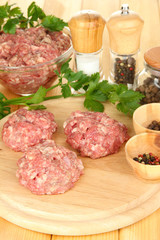 Raw meatballs with spices on wooden table