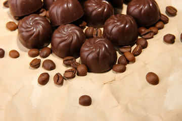 Chocolate candies and coffee beans, on beige paper background