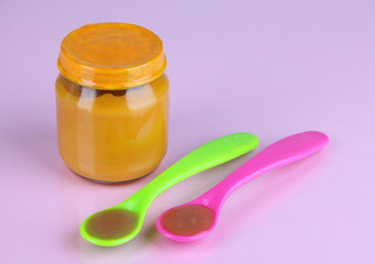 Baby food with weaning spoons on purple background