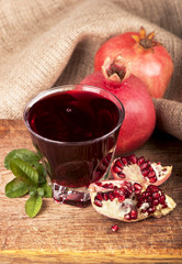 Garnet juice in a glass and pomegranate on wooden boards, on