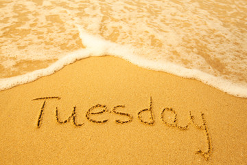 Tuesday - written in sand on beach texture.