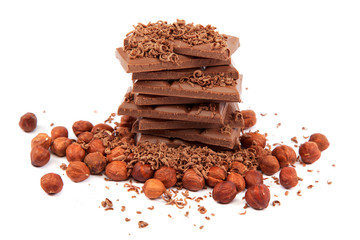 Stack of chocolate tiles with hazelnuts on a white background.