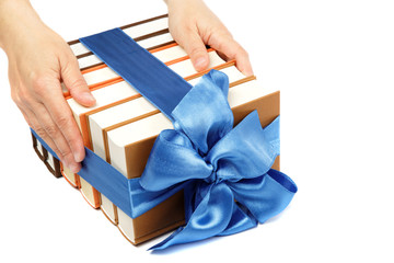 Book as a gift. A stack of books in female hands on a white back