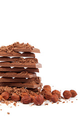 Stack of chocolate tiles with hazelnuts on a white background.