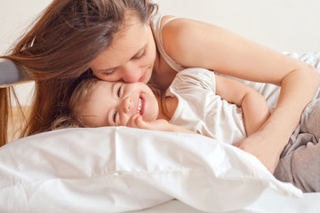A happy family.  Young Woman and litle girl  in bed