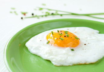 Fried egg with chives on green plate