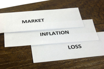 Paper cutting with market, inflation and loss written on it