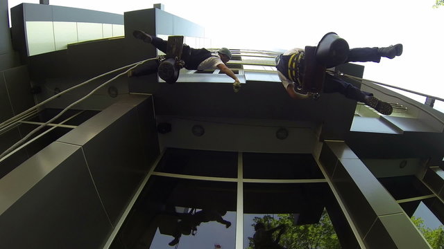 Window Cleaners Outside of a Building Hanging From a